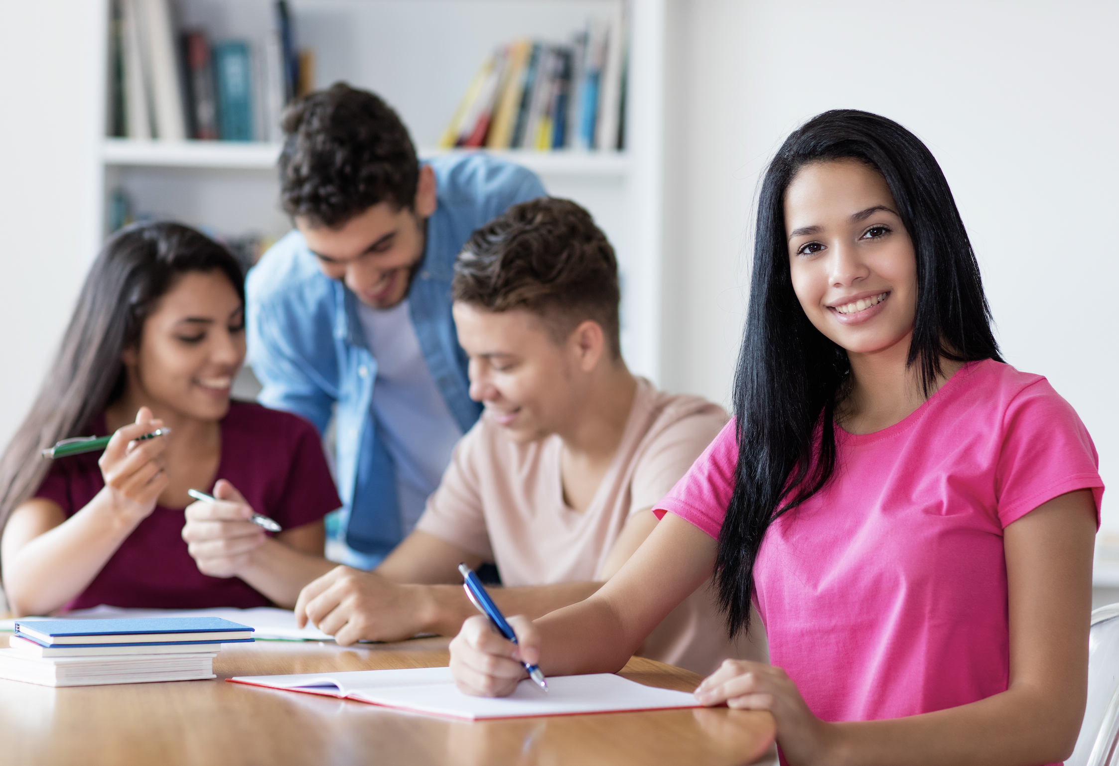 Teen student in pink shirt studying in class with peers
